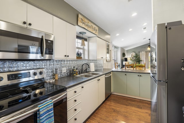 kitchen with lofted ceiling, stainless steel appliances, pendant lighting, white cabinetry, and backsplash