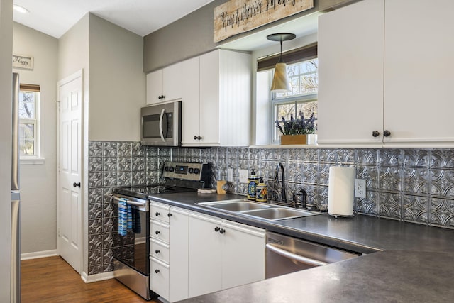 kitchen featuring stainless steel appliances, tasteful backsplash, sink, pendant lighting, and white cabinetry