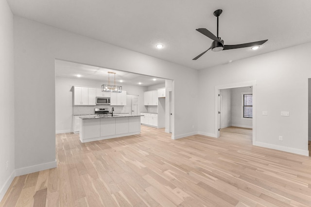 unfurnished living room featuring light hardwood / wood-style floors, sink, and ceiling fan