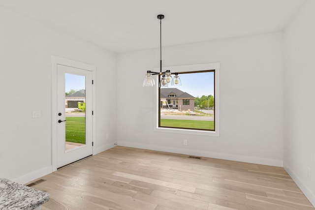 unfurnished dining area with light hardwood / wood-style floors and an inviting chandelier