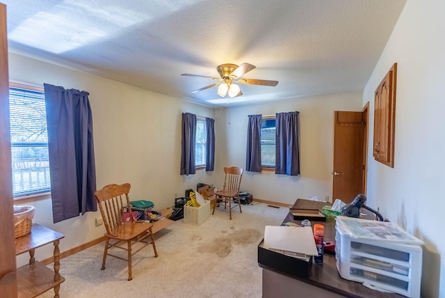 living area with a textured ceiling, light colored carpet, a wealth of natural light, and ceiling fan