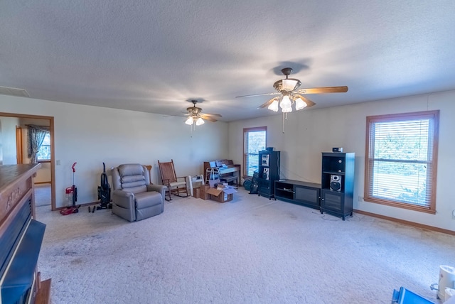 living area featuring carpet, a textured ceiling, and ceiling fan