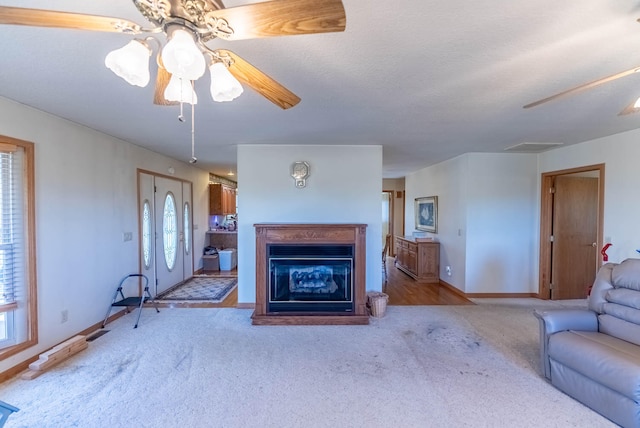 unfurnished living room with plenty of natural light, light colored carpet, a textured ceiling, and ceiling fan