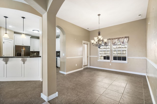 unfurnished dining area featuring a chandelier, arched walkways, visible vents, and dark tile patterned floors