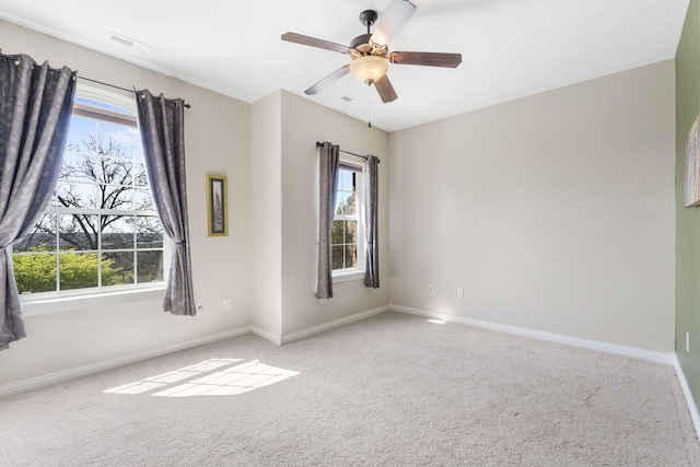 empty room with a healthy amount of sunlight, visible vents, baseboards, and carpet flooring