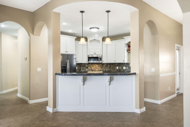 kitchen featuring a breakfast bar, white cabinets, appliances with stainless steel finishes, backsplash, and decorative light fixtures