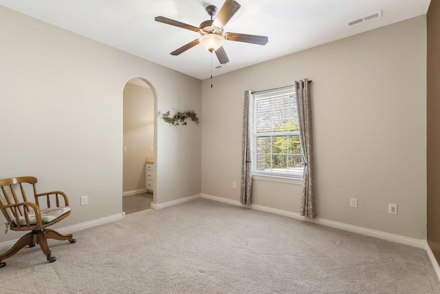 unfurnished room with carpet, arched walkways, visible vents, ceiling fan, and baseboards