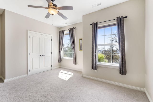 unfurnished bedroom featuring ceiling fan, carpet flooring, visible vents, baseboards, and a closet