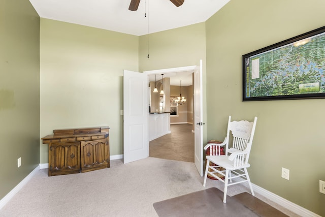 sitting room with carpet floors, a high ceiling, baseboards, and ceiling fan with notable chandelier