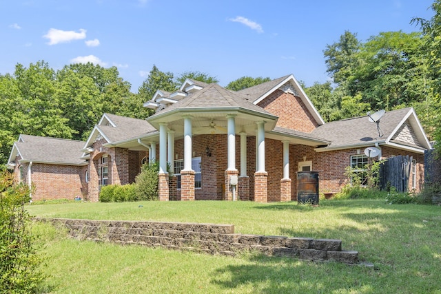 view of front of home featuring a shingled roof, a front yard, and brick siding