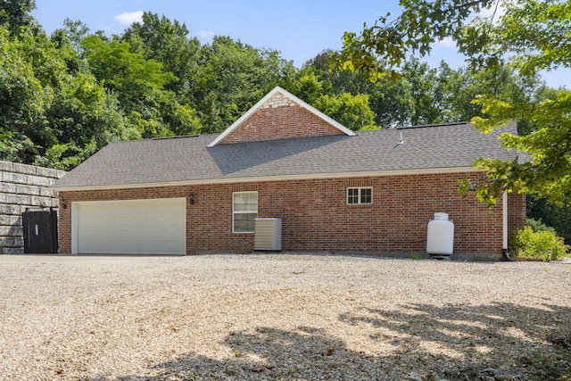 view of side of property featuring brick siding, roof with shingles, and an attached garage