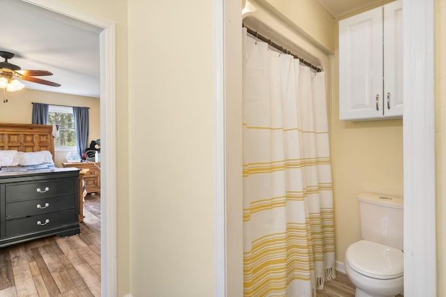 bathroom with curtained shower, wood-type flooring, ceiling fan, and toilet