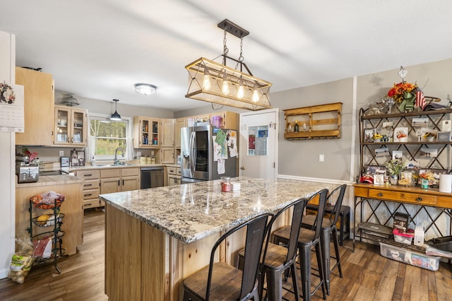 kitchen with a sink, a kitchen bar, stainless steel fridge with ice dispenser, dishwasher, and wood-type flooring