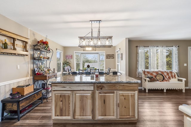kitchen with a kitchen island, stone counters, pendant lighting, and dark wood-style flooring