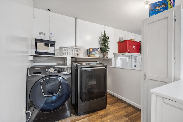 laundry area featuring washing machine and clothes dryer, baseboards, and wood finished floors