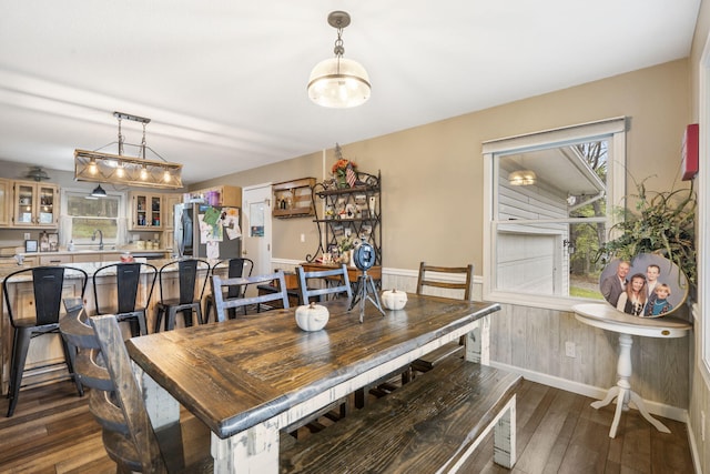 dining space featuring dark wood-type flooring, plenty of natural light, a wainscoted wall, and baseboards