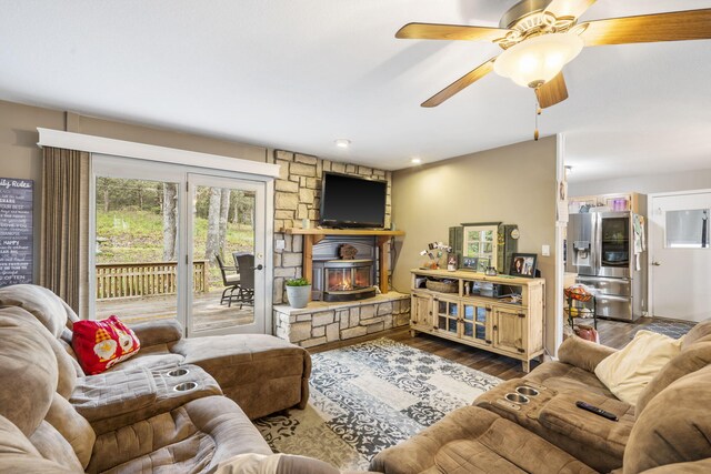 living area featuring dark wood finished floors, a wood stove, and a ceiling fan
