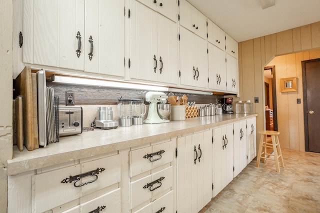 kitchen with wood walls and white cabinetry