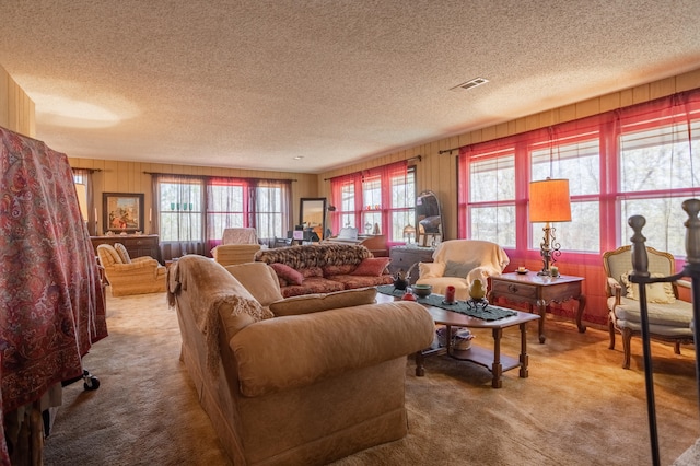 carpeted living room with wooden walls and a textured ceiling