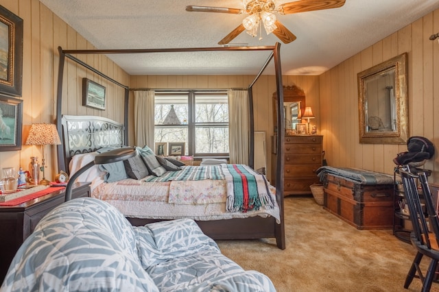 carpeted bedroom with wooden walls, a textured ceiling, and ceiling fan