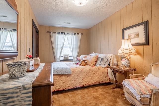 bedroom featuring carpet floors, wood walls, and a textured ceiling