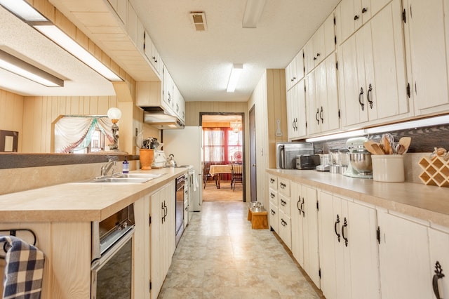 kitchen featuring wooden walls, sink, and a textured ceiling