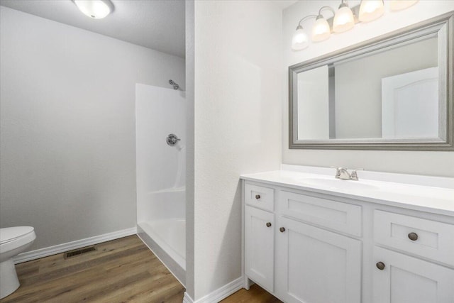 bathroom featuring vanity, walk in shower, toilet, and wood-type flooring