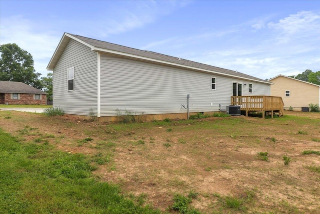 back of house featuring cooling unit, a lawn, and a wooden deck