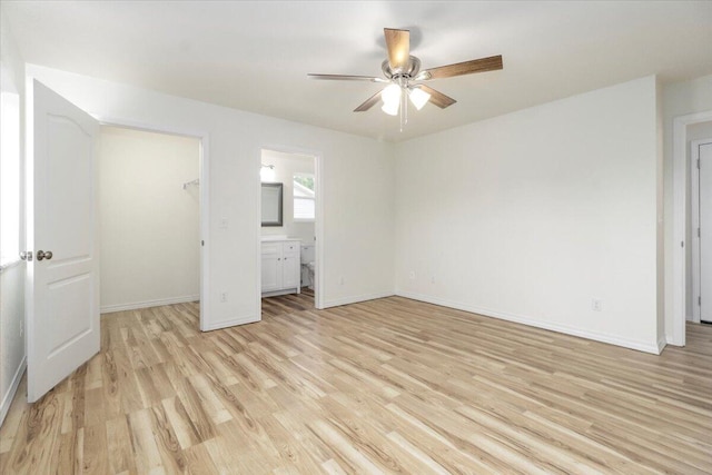 unfurnished bedroom featuring a walk in closet, ceiling fan, light hardwood / wood-style flooring, a closet, and connected bathroom