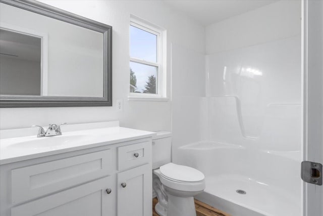 bathroom featuring hardwood / wood-style floors, vanity, toilet, and a shower