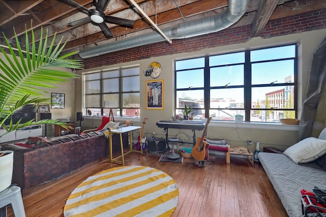 living room with ceiling fan, brick wall, and wood-type flooring