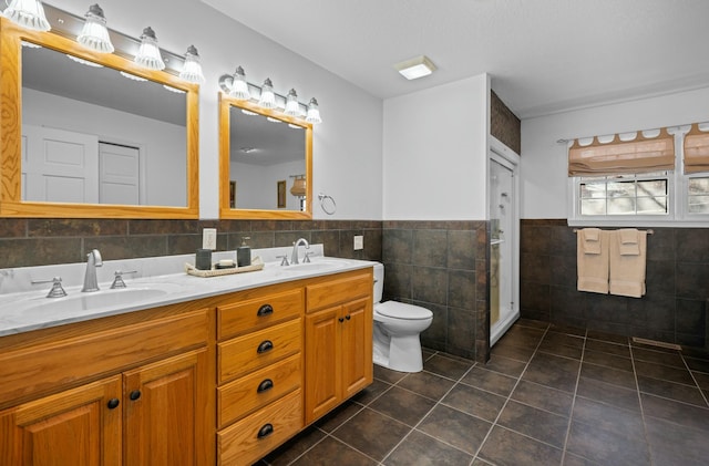 bathroom with tile walls, vanity, tile patterned floors, toilet, and walk in shower