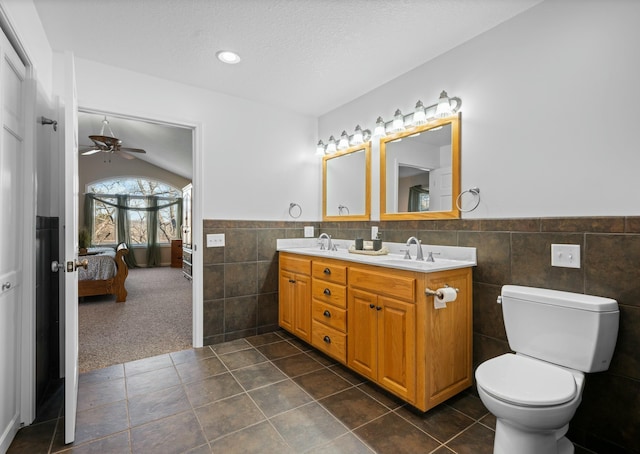 bathroom with tile walls, tile patterned flooring, vanity, vaulted ceiling, and toilet