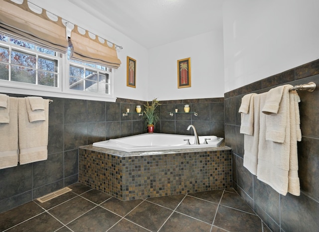 bathroom featuring tile patterned flooring, tiled tub, and tile walls