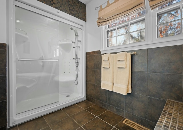 bathroom featuring a shower with door, tile walls, and tile patterned floors