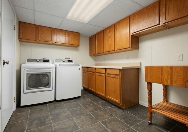 laundry room featuring cabinets, dark tile patterned floors, and washing machine and clothes dryer