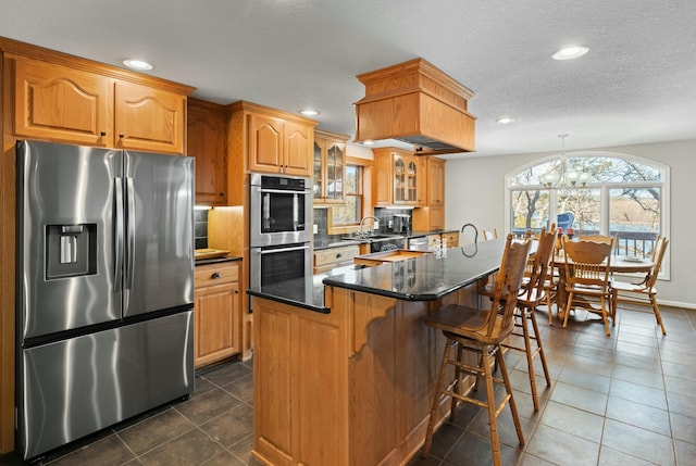 kitchen with sink, a center island, dark stone countertops, appliances with stainless steel finishes, and decorative backsplash