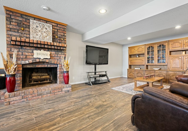 living room featuring a fireplace, wood-type flooring, and a textured ceiling