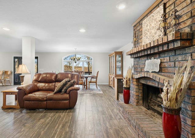 living room with dark hardwood / wood-style flooring, a notable chandelier, a fireplace, and a textured ceiling