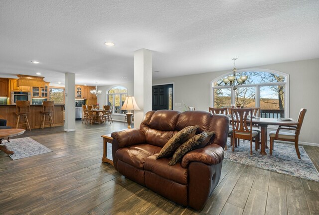 living room featuring dark wood-type flooring, a chandelier, and a textured ceiling