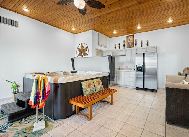 kitchen featuring light tile patterned floors, wood ceiling, ceiling fan, white cabinetry, and stainless steel fridge with ice dispenser