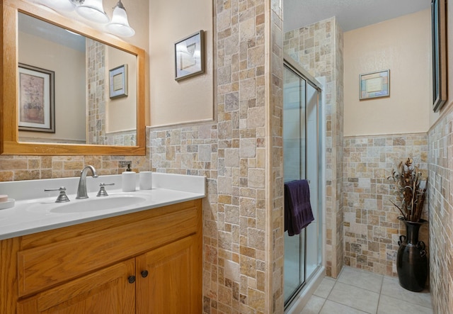 bathroom featuring tile patterned flooring, vanity, tile walls, and walk in shower