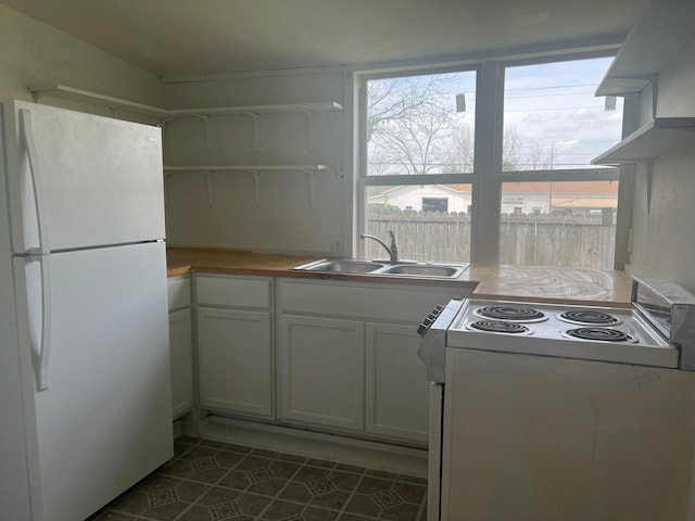 kitchen featuring dark tile patterned flooring, sink, white appliances, and white cabinetry