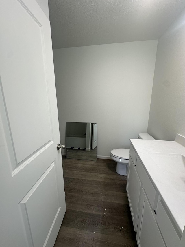 bathroom with vanity, hardwood / wood-style floors, a textured ceiling, and toilet