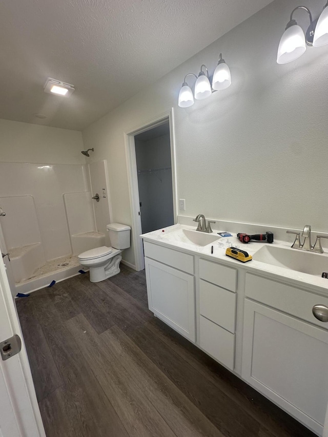 bathroom featuring toilet, a shower, a textured ceiling, vanity, and hardwood / wood-style floors