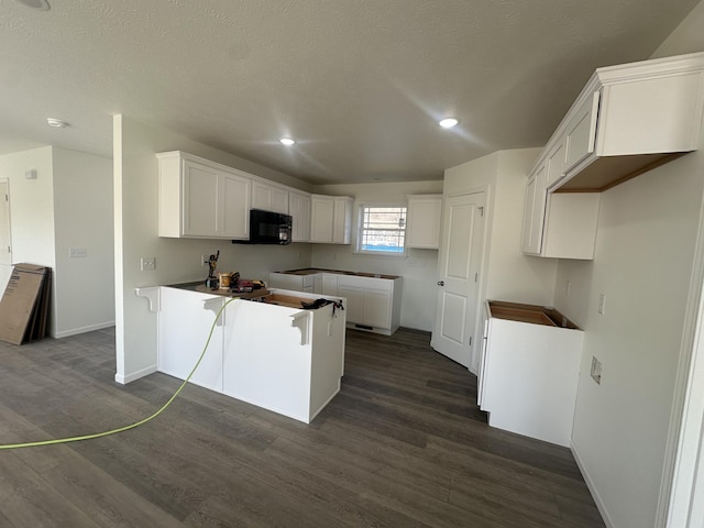 kitchen with dark hardwood / wood-style floors, white cabinets, and a textured ceiling