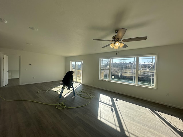 unfurnished living room featuring dark wood-type flooring and ceiling fan