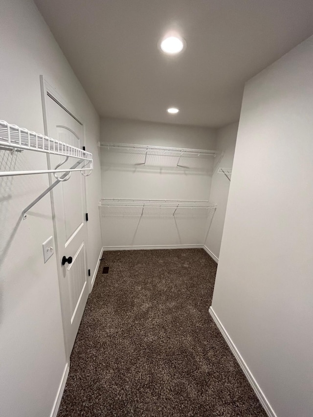 walk in closet featuring dark carpet