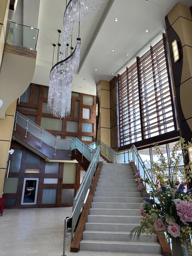 staircase featuring recessed lighting, a high ceiling, tile patterned flooring, and a notable chandelier