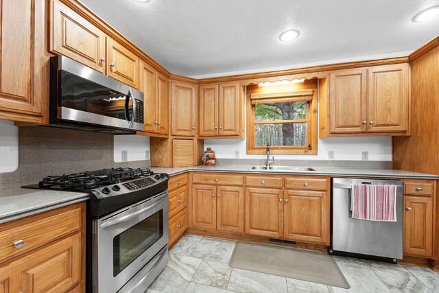 kitchen with a textured ceiling, appliances with stainless steel finishes, and sink